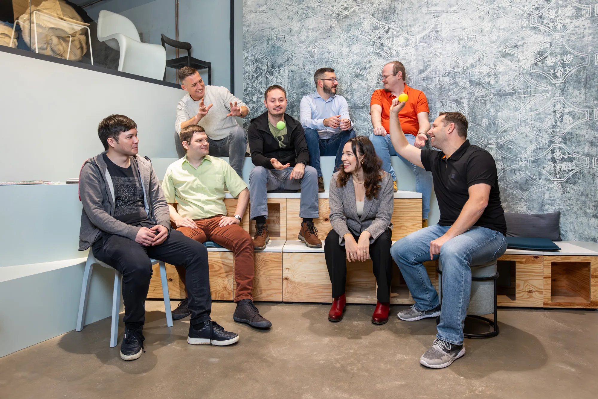 Gruppenfoto des blecon-Teams in einem modernen Büro; mehrere Teammitglieder sitzen und stehen entspannt zusammen und lächeln in die Kamera.