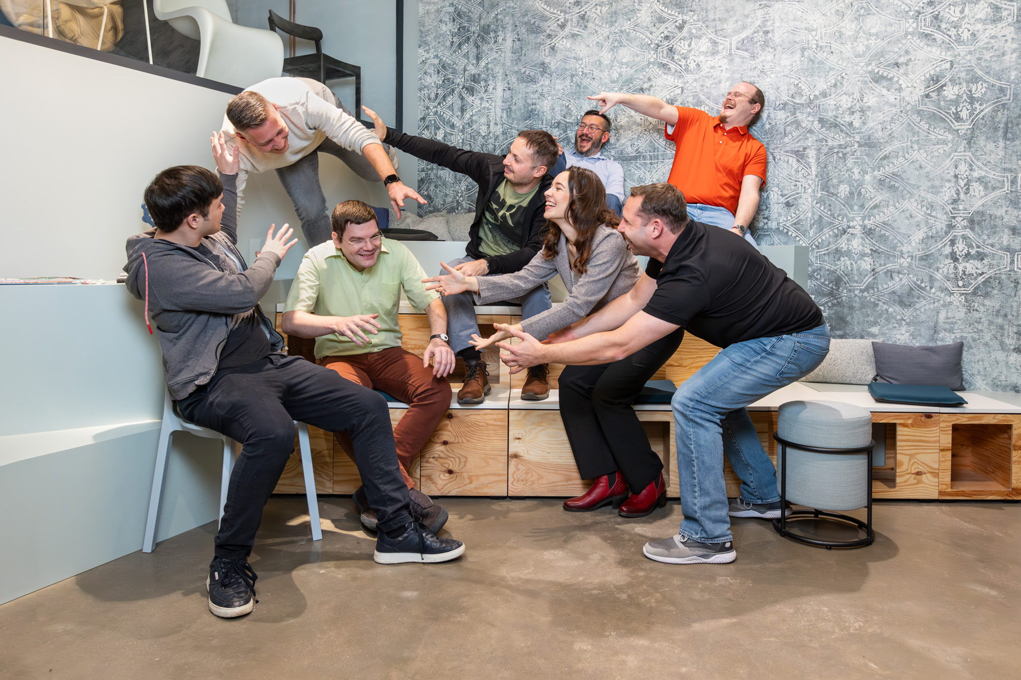 Gruppenfoto des blecon-Teams in einem modernen Büro; mehrere Teammitglieder sitzen und stehen entspannt zusammen und lächeln in die Kamera.